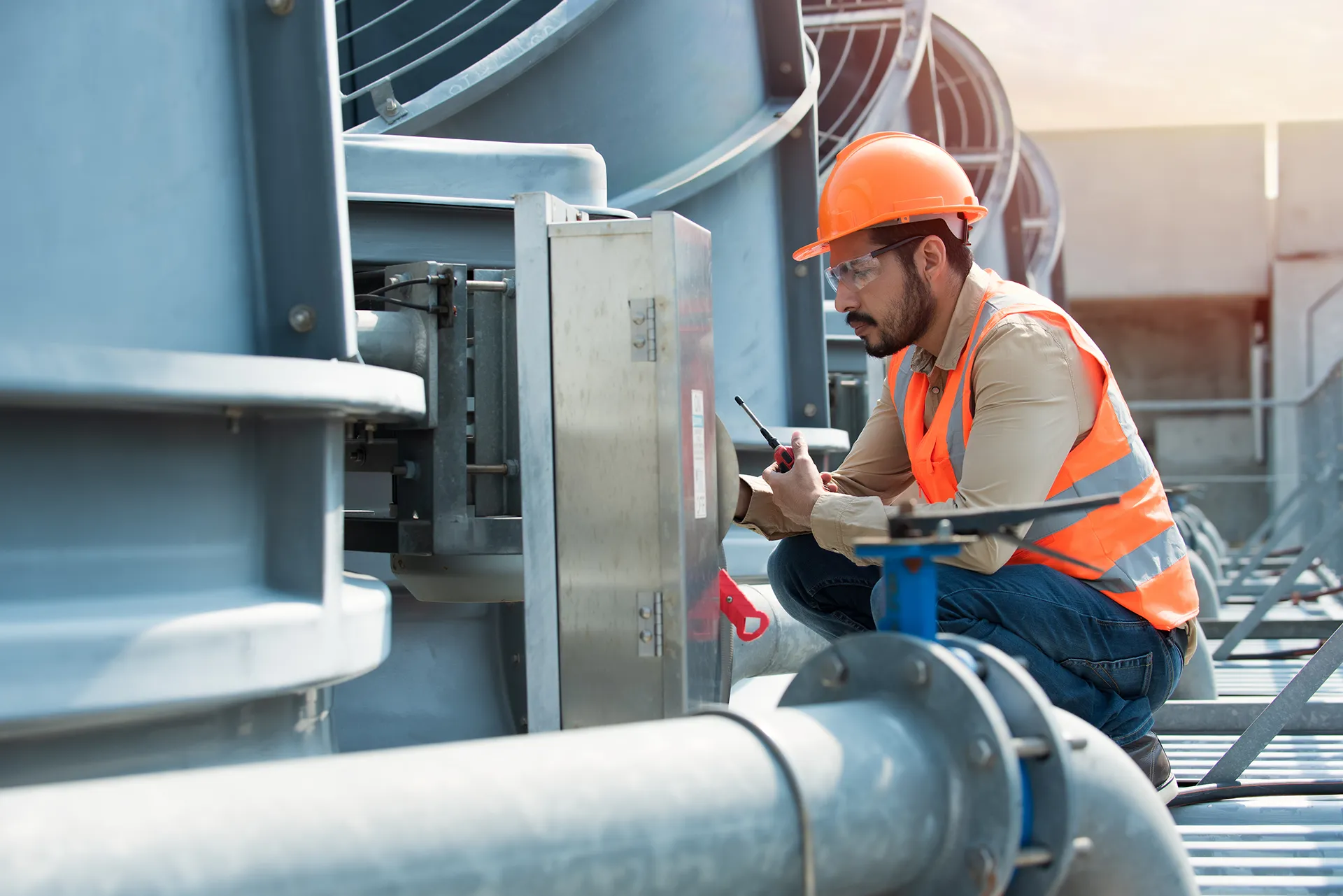 L'ingegnere che sta controllando il condizionatore a torre di raffreddamento dell'industria è un refrigeratore d'aria a torre di raffreddamento ad acqua HVAC di un grande edificio industriale per controllare il sistema dell'aria.