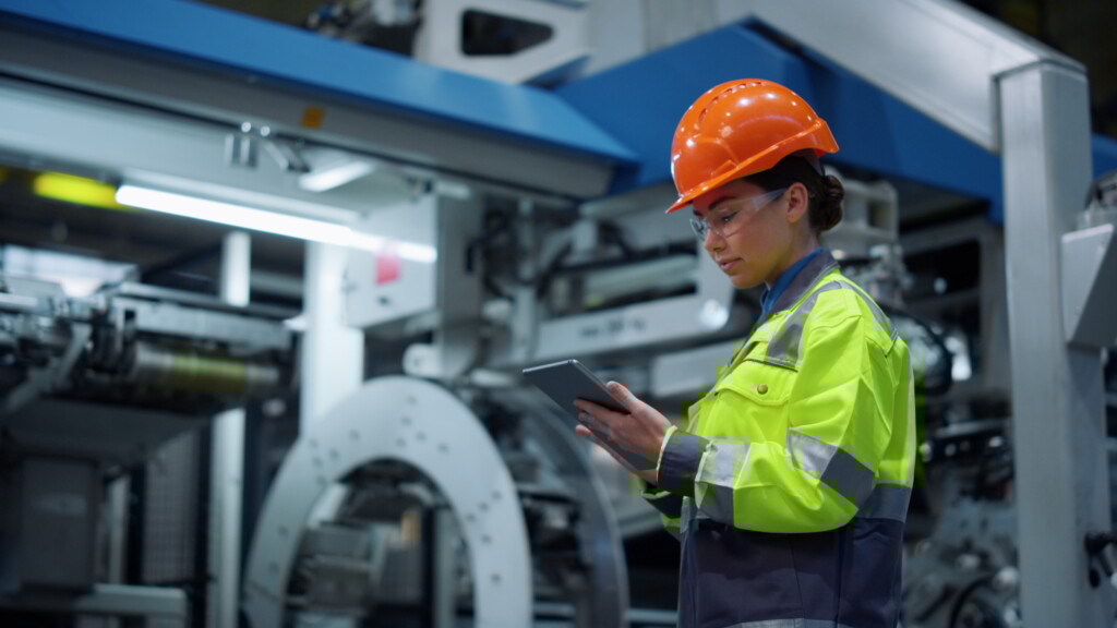 A woman views a tablet in a factory setting.